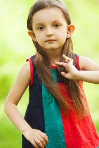 Portrait of funny, sweet, little, charismatic girl touching her long hair.