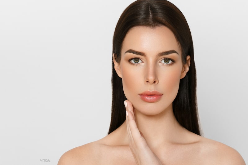 Woman with clean skin standing against a gray background