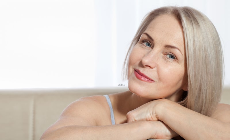 An attractive older woman resting her chin on her hands.